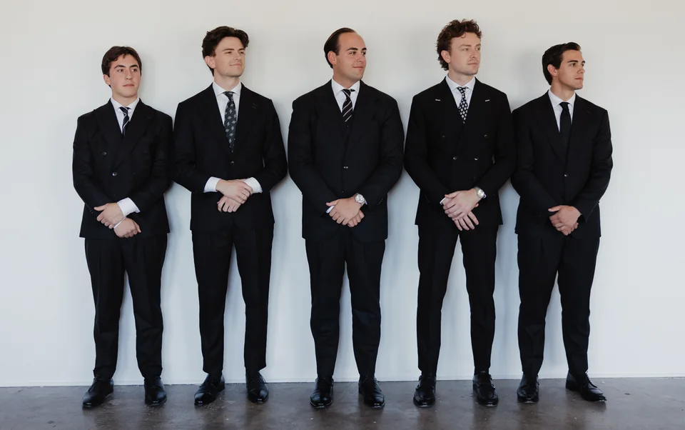 A full-length group composition in dark suits.