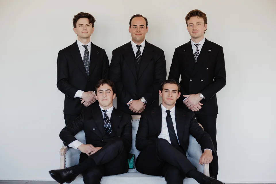 Seated and standing group composition in dark suits.