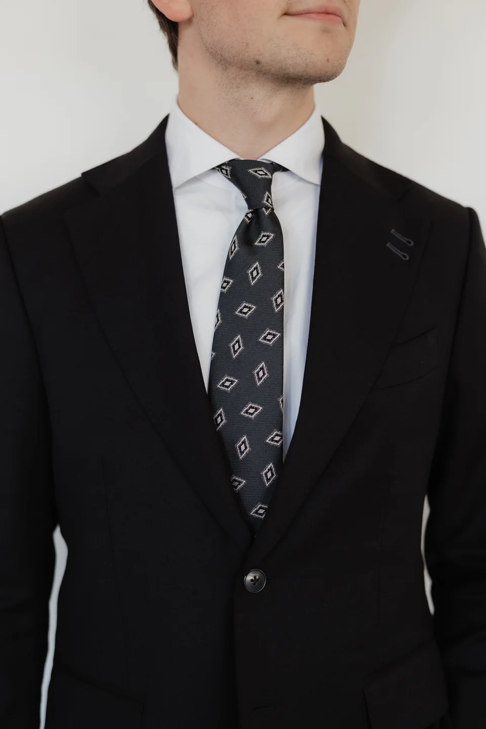 Dark suit lapels and patterned tie detail.
