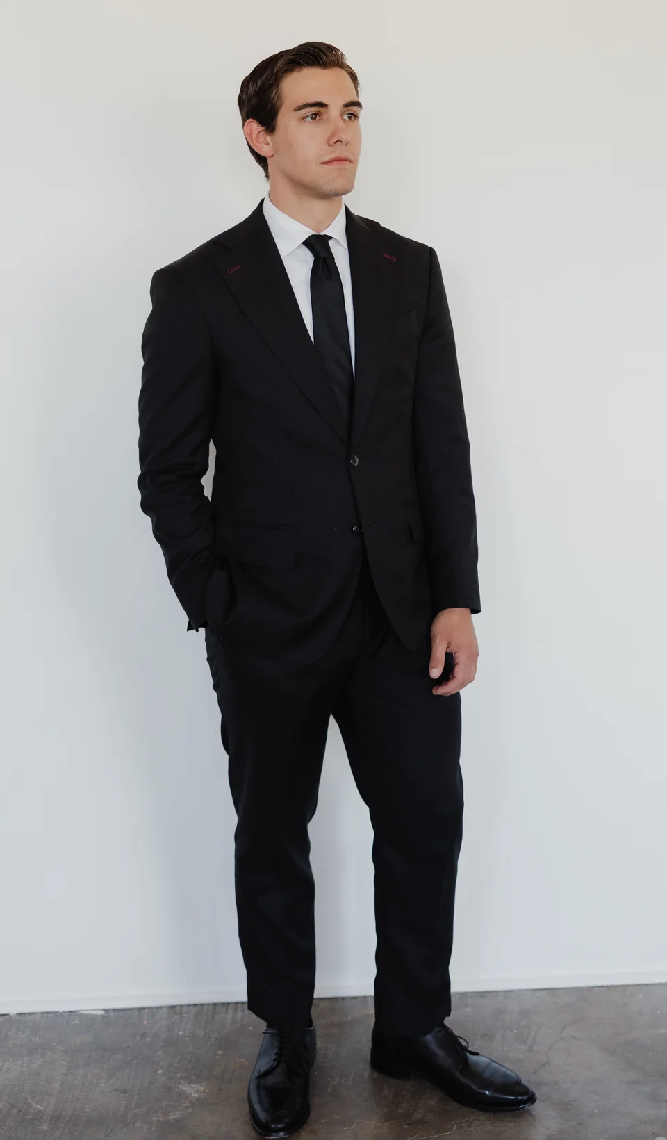 Full-length dark suit with a patterned tie.