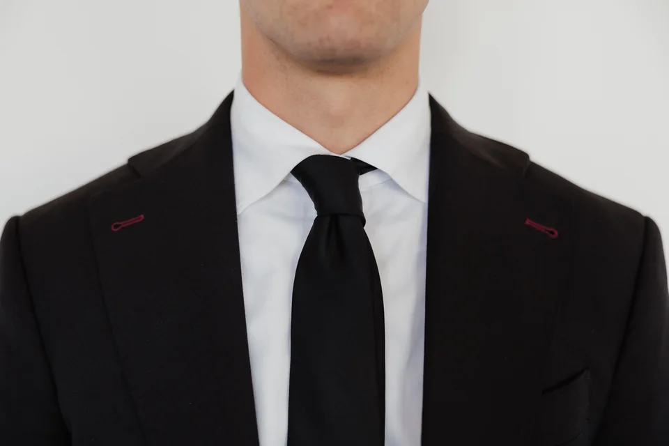 Dark jacket lapels with a black tie.