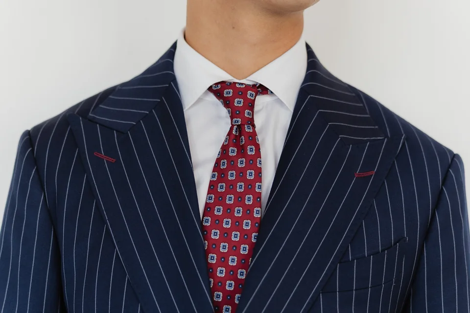 Navy pinstripe lapels with a red patterned tie.