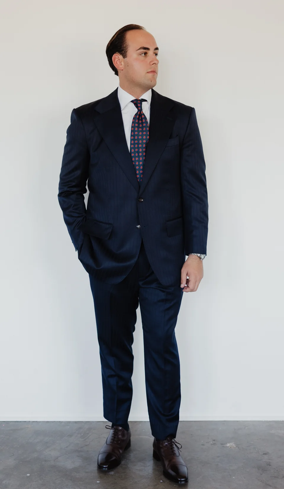 Full-length navy suit with a patterned tie.