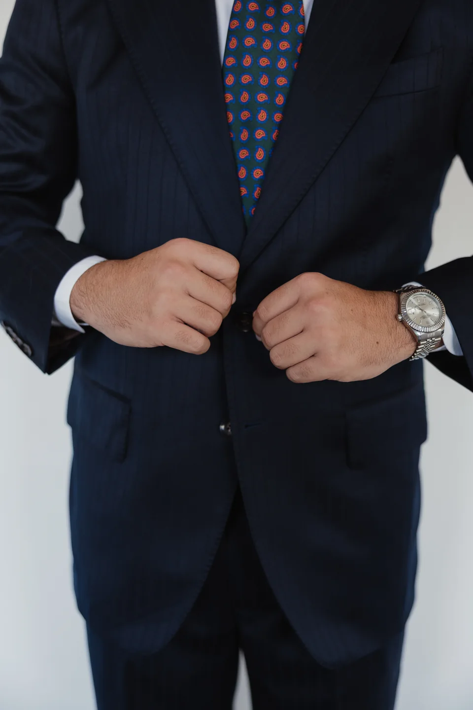 Navy suit, patterned tie and wristwatch detail.
