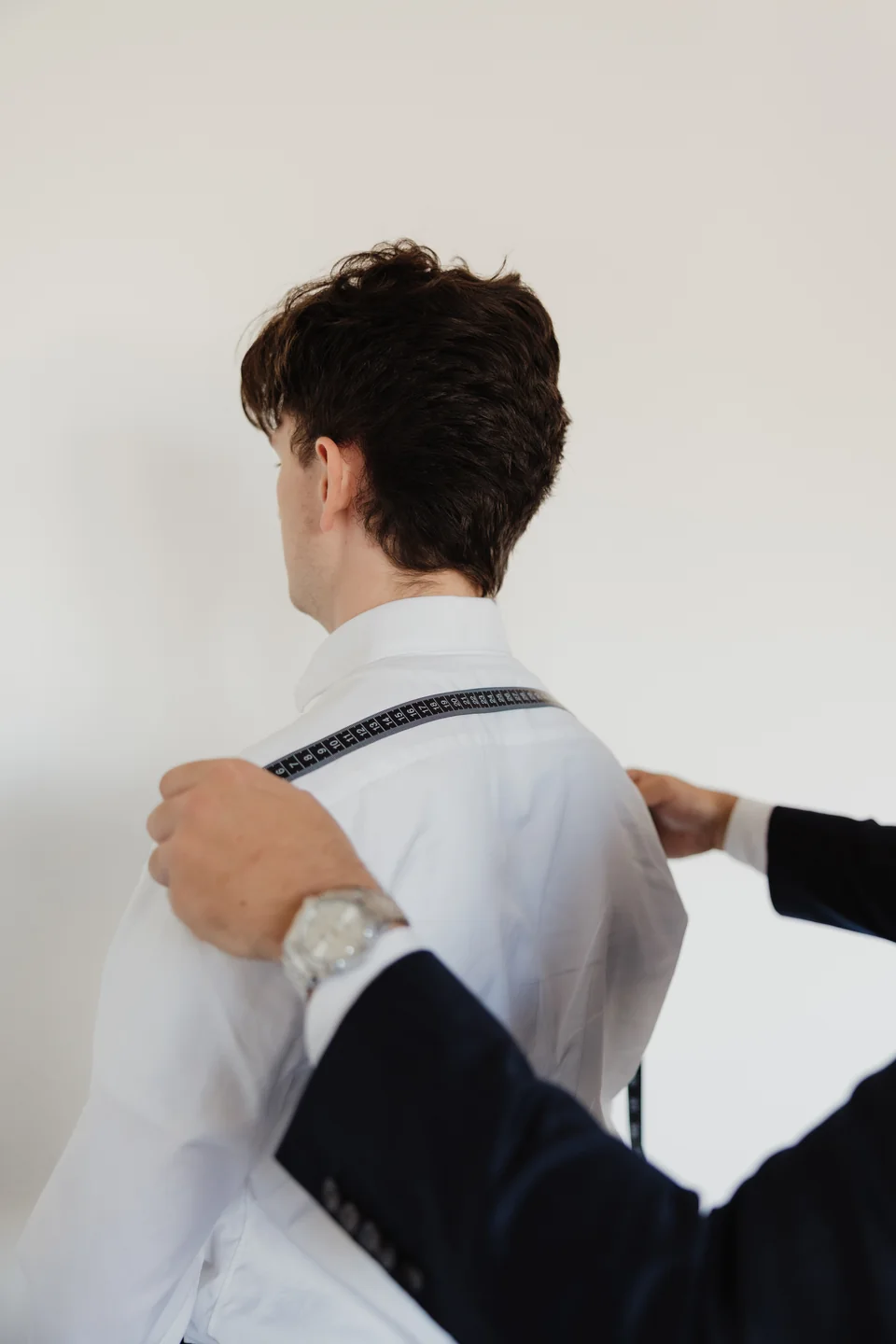 Measuring tape across the shoulders of a white shirt.