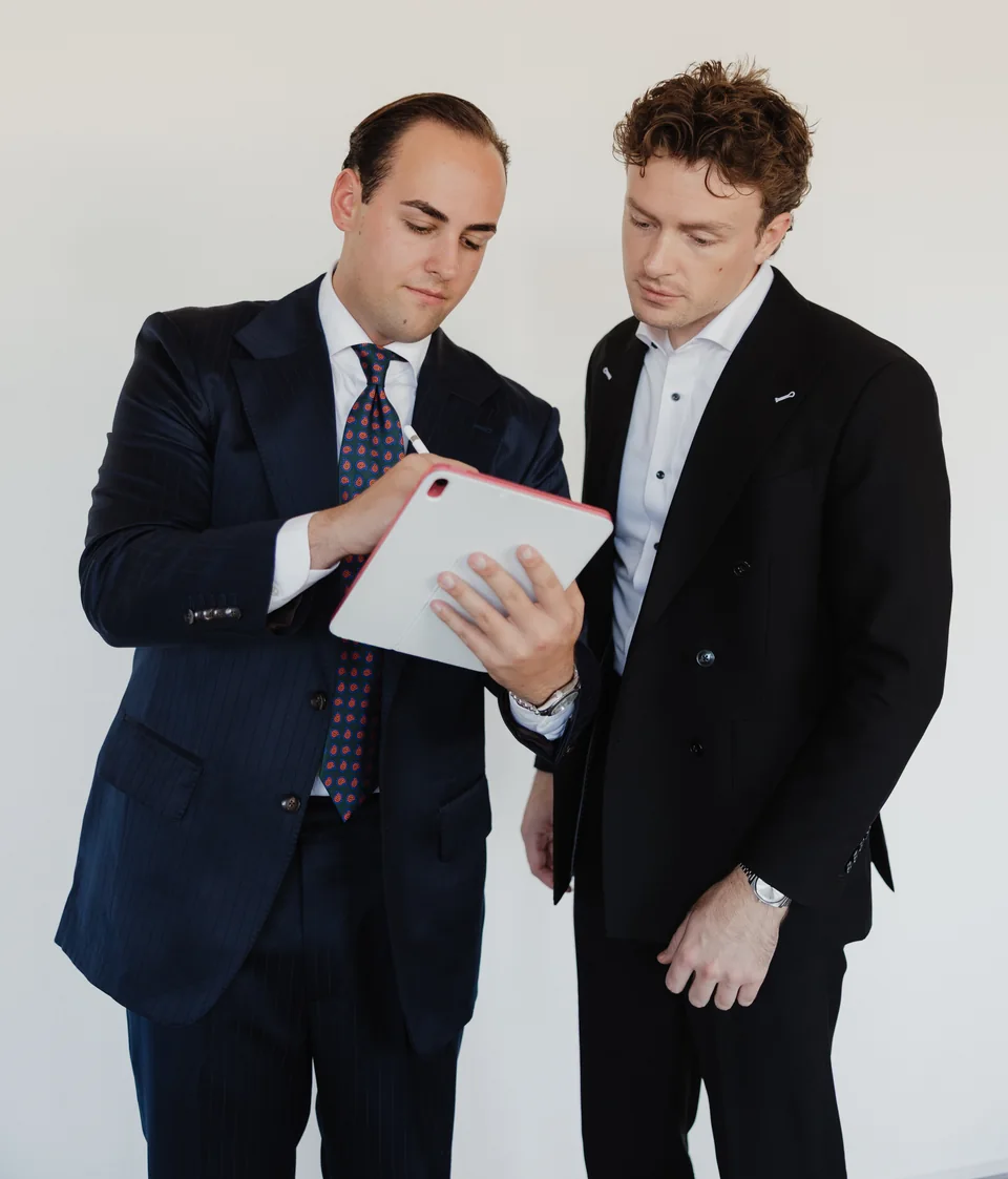 Two people reviewing suit choices on a tablet.