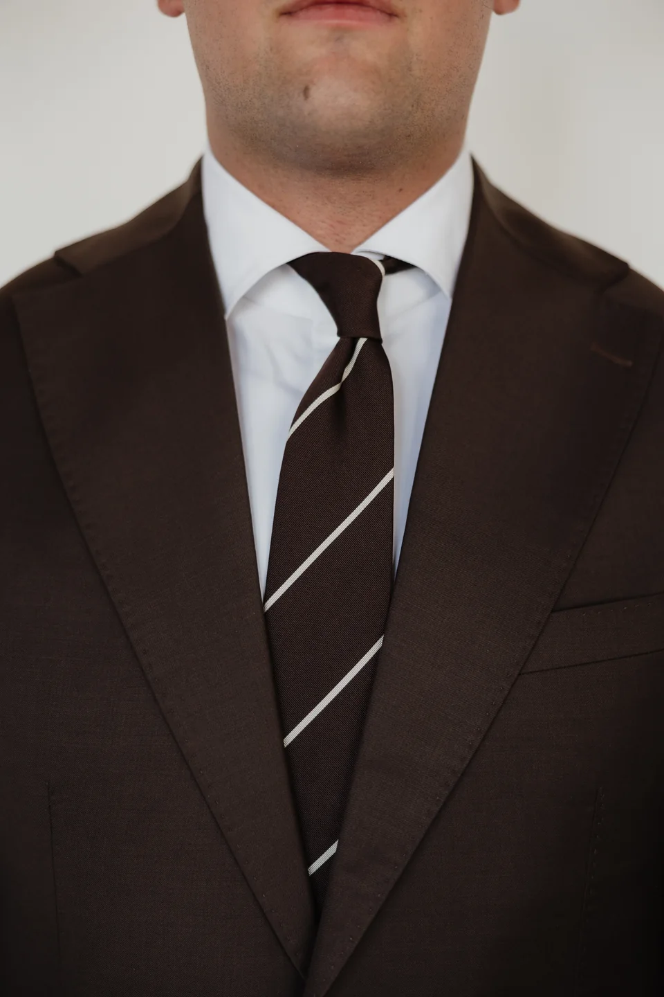 Brown suit lapels with a striped tie.