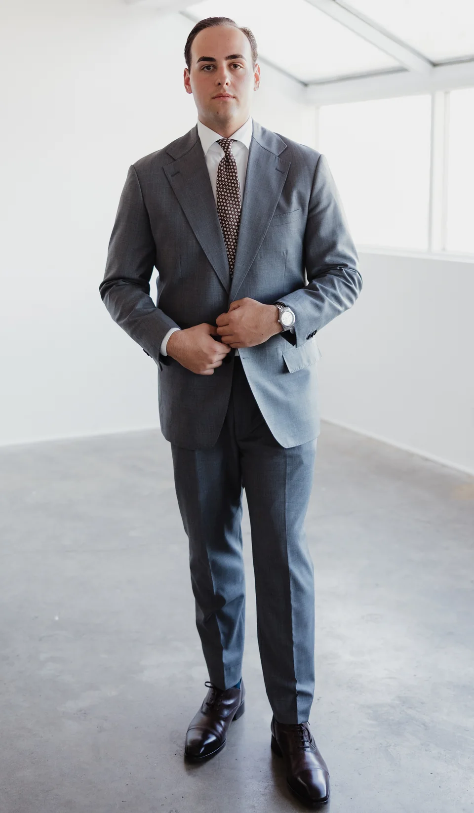Full-length gray suit in a bright, windowed setting with the shoes visible.