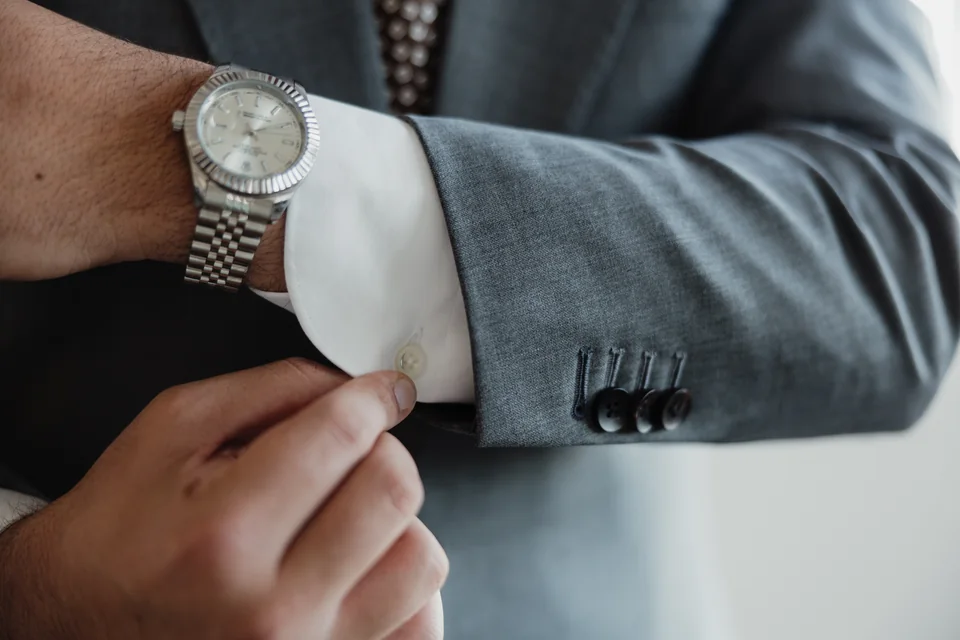 Gray jacket cuff, shirt cuff and wristwatch detail.